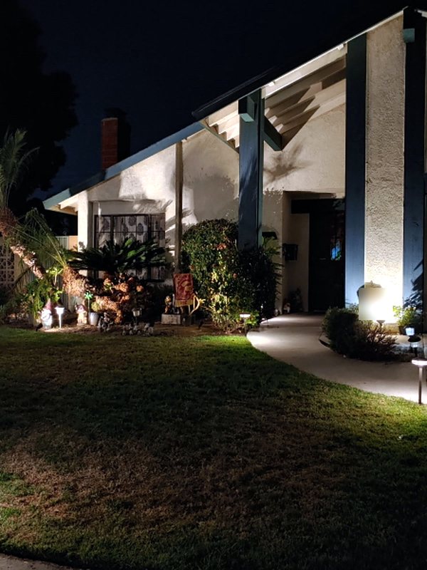 Low-voltage path lights and uplighting along a front walkway and garden at night