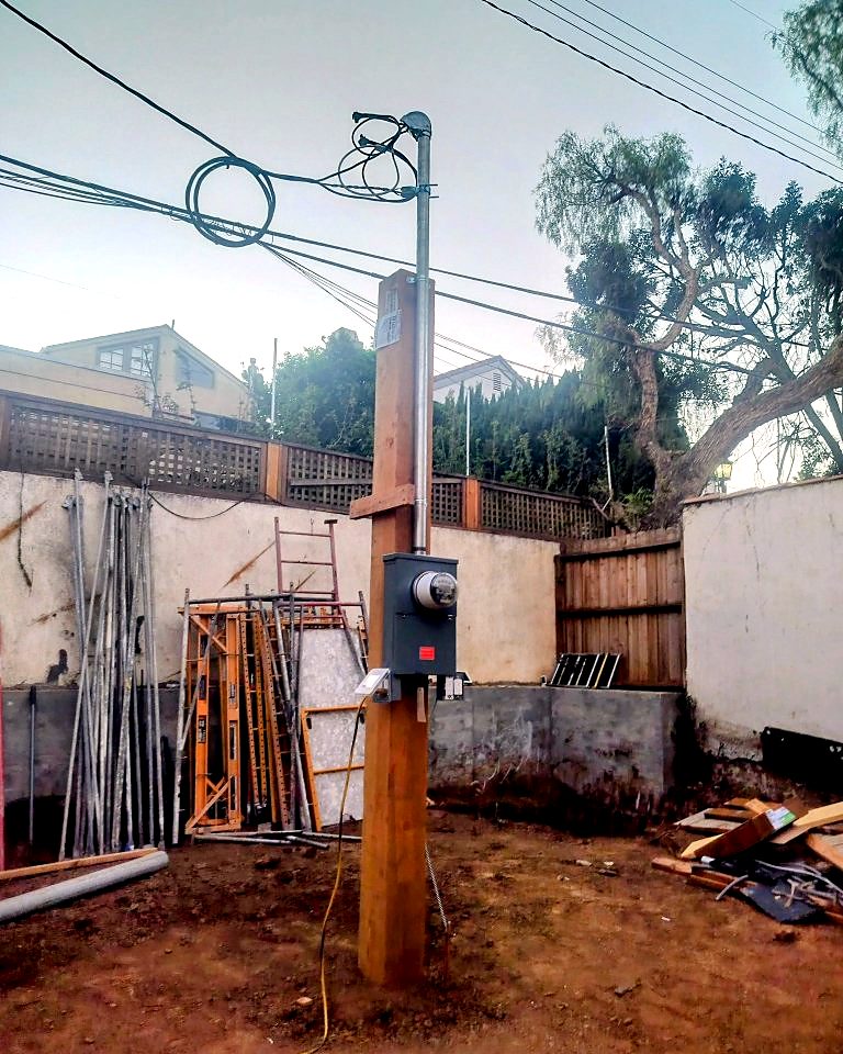 New electrical service pole with meter installed on a construction site