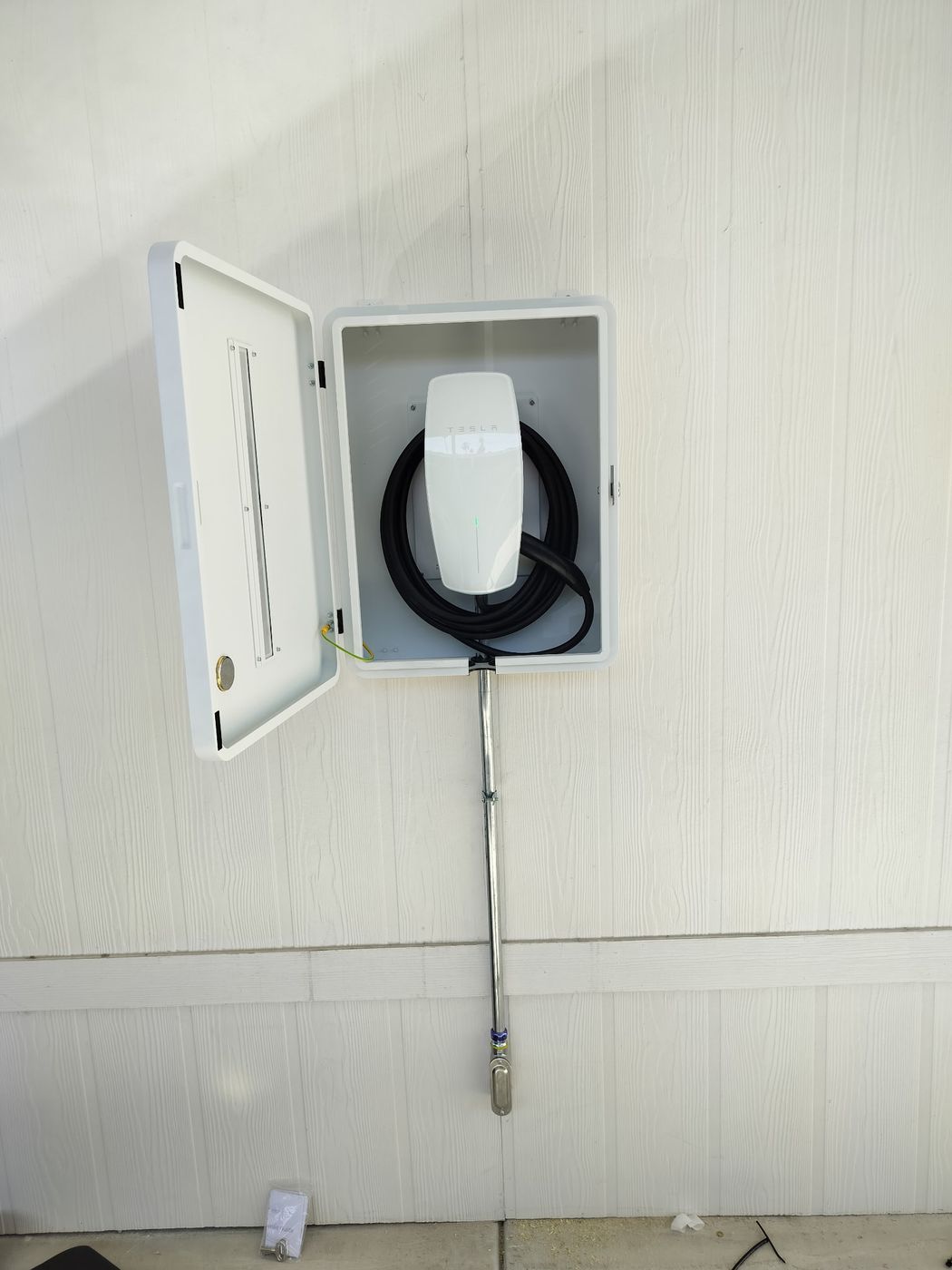 Tesla Wall Connector EV charger mounted in a weatherproof outdoor enclosure