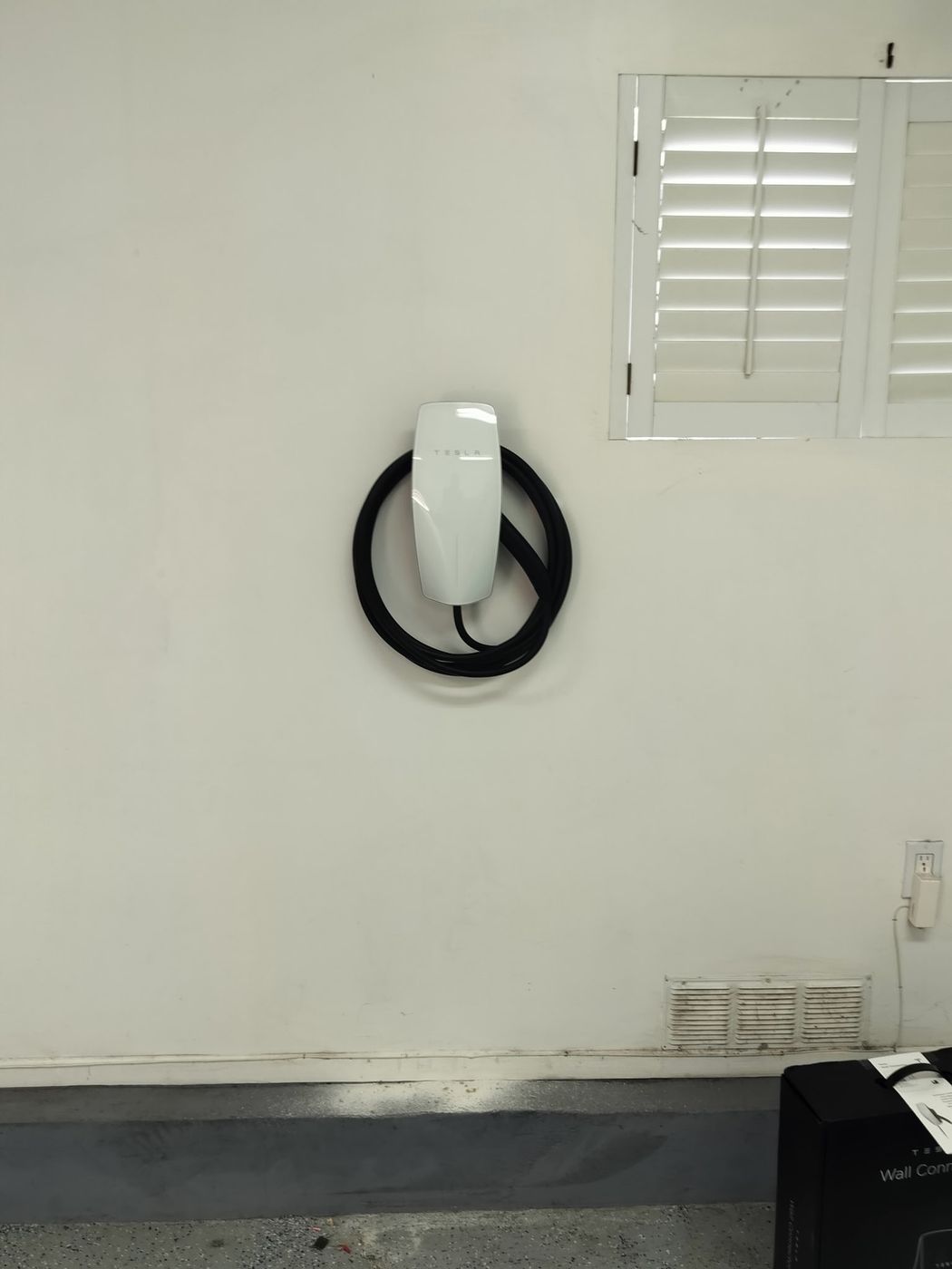 Tesla Wall Connector EV charger mounted on an interior garage wall